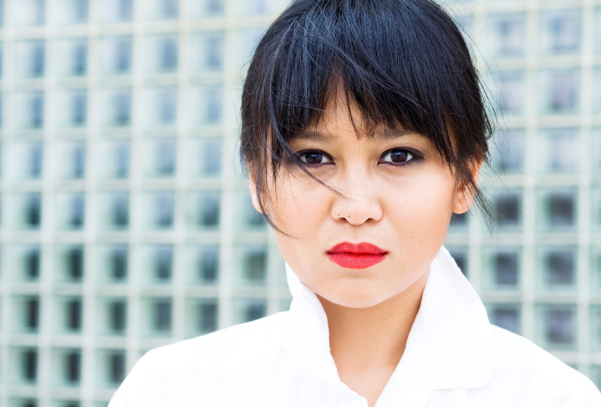 Asian woman with layered wispy bangs wearing white clothes.