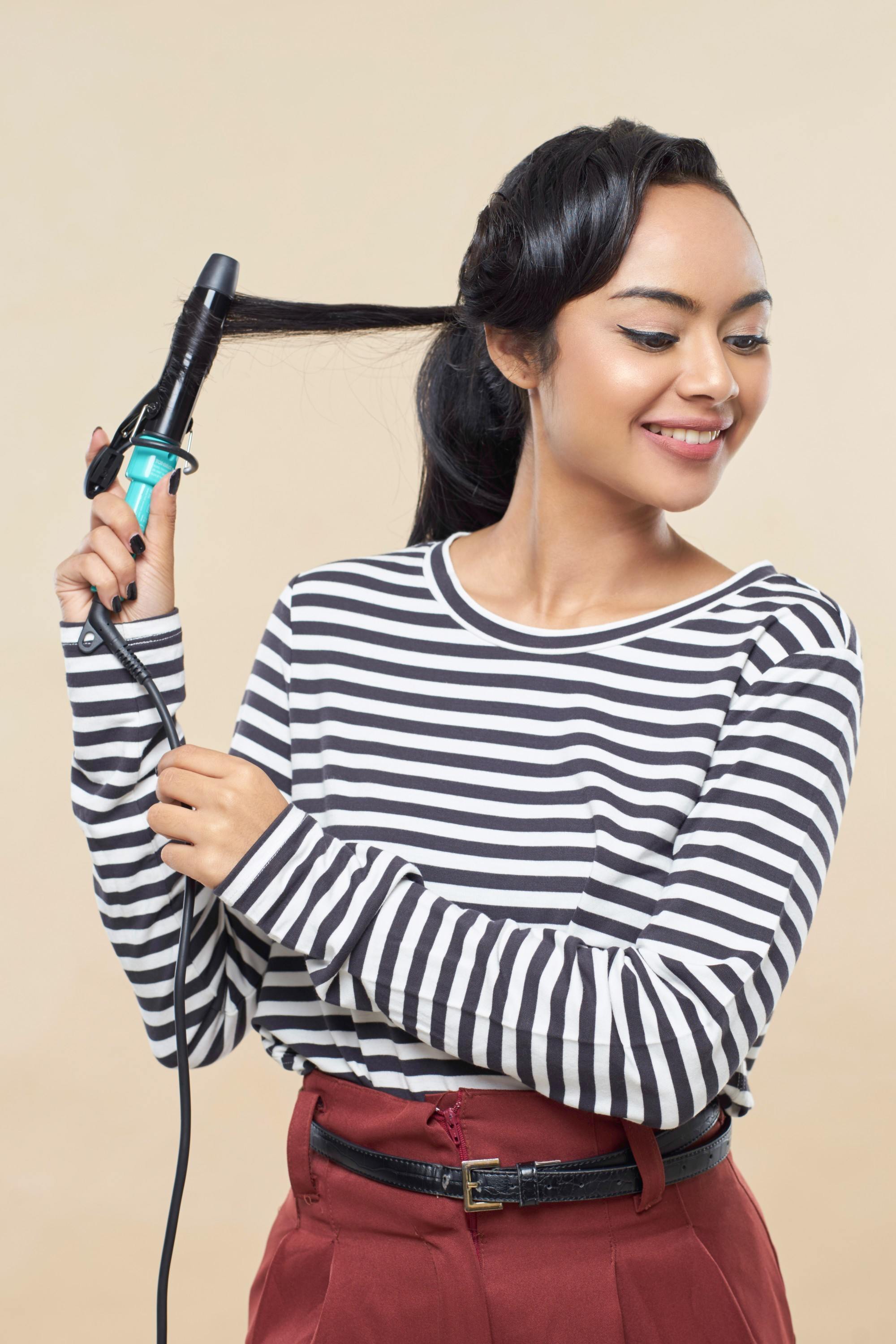 hair fall: Girl is curling her hair with a curling wand