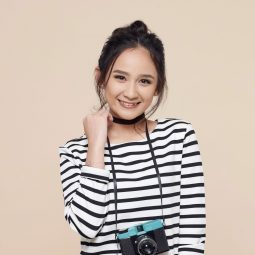 Asian woman with a messy bun wearing a striped shirt and denim pants