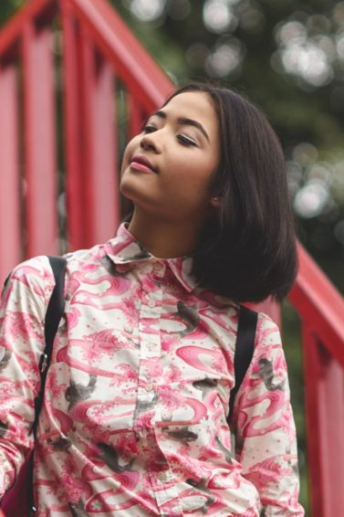 How to style a bob: Closeup shot of an Asian woman with short black hair wearing a printed polo outdoors