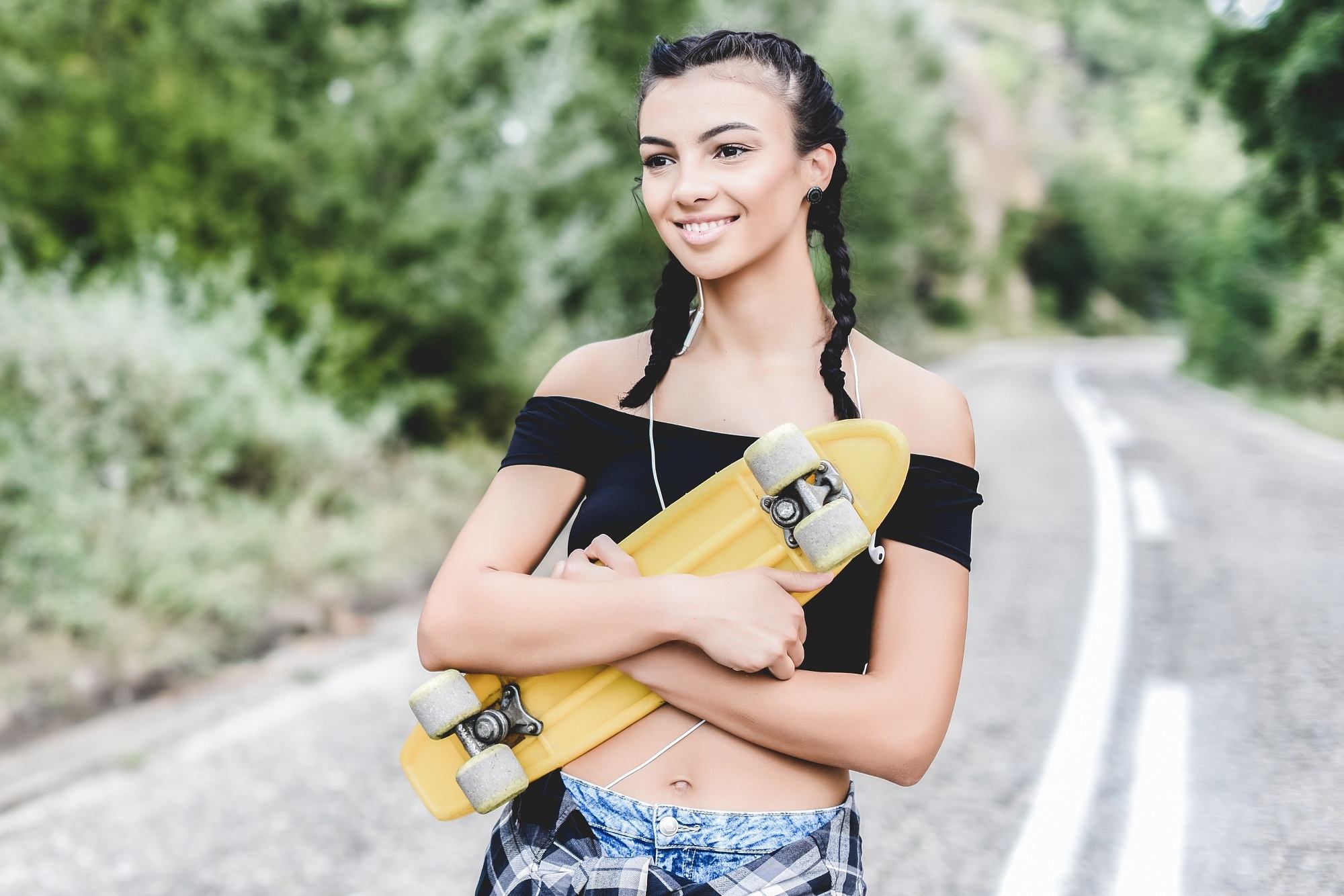 Hairstyles for skaters: Woman with black hair in boxer braid holding a skateboard