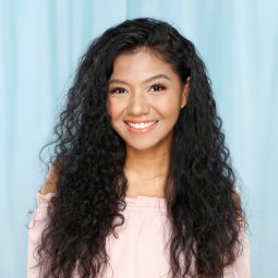 Asian woman with long curly hair wearing a pink dress