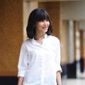 Party hairstyles for short hair: Asian woman with a long bob with bangs in a blowout hairstyle wearing a white blouse and denim jeans