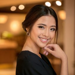 Party hairstyles for short hair :Asian woman with hair in chignon smiling at a posh lobby