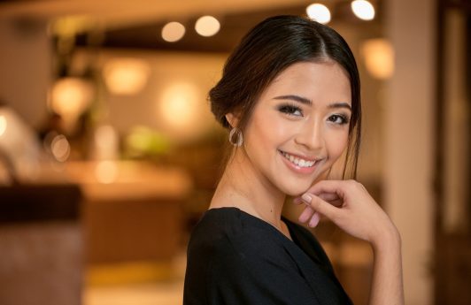 Party hairstyles for short hair :Asian woman with hair in chignon smiling at a posh lobby