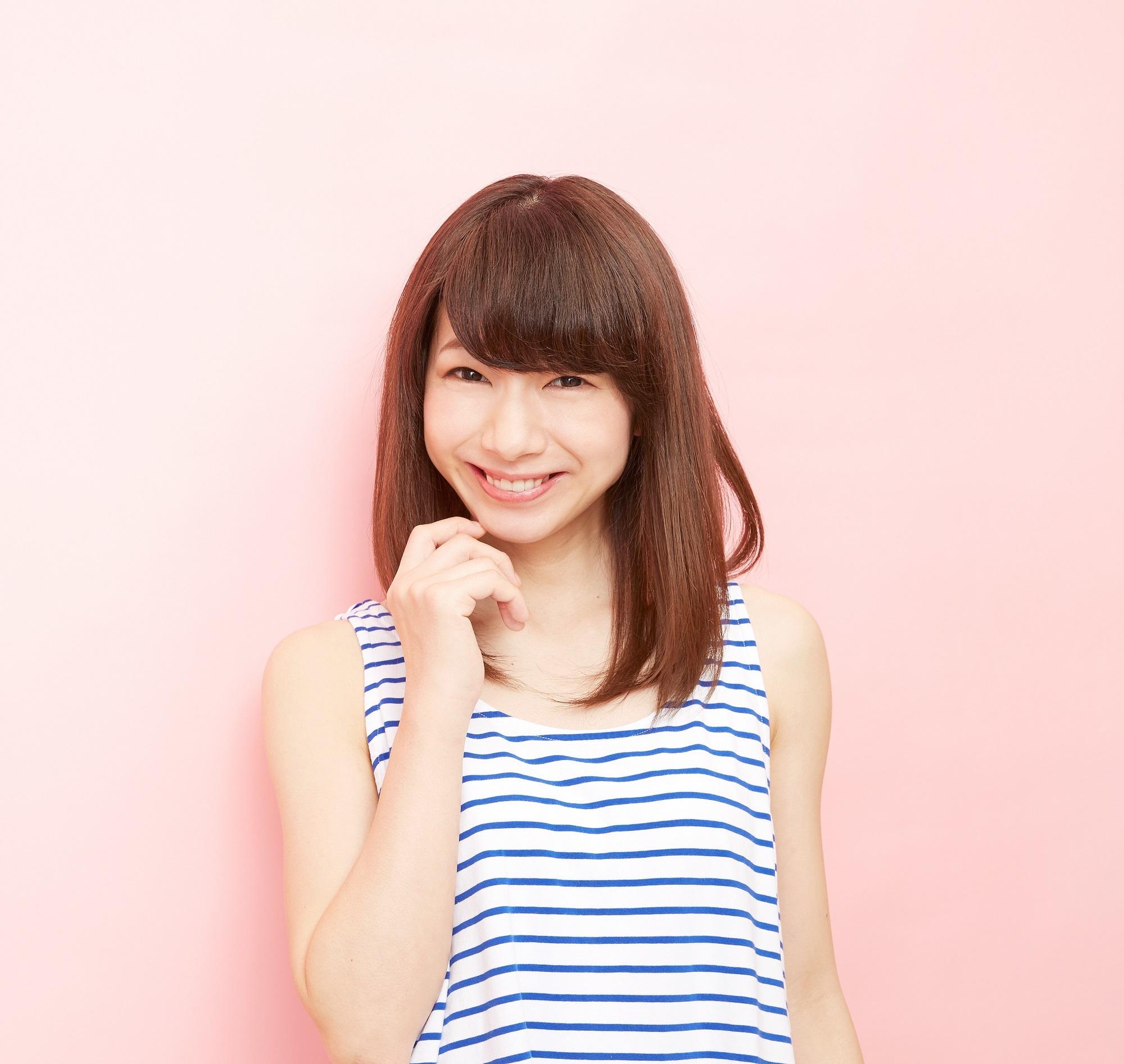 Meilleures coupes de cheveux pour cheveux longs : fille asiatique portant une chemise sans manches rayée avec des cheveux mi-longs avec une frange debout sur un fond rose