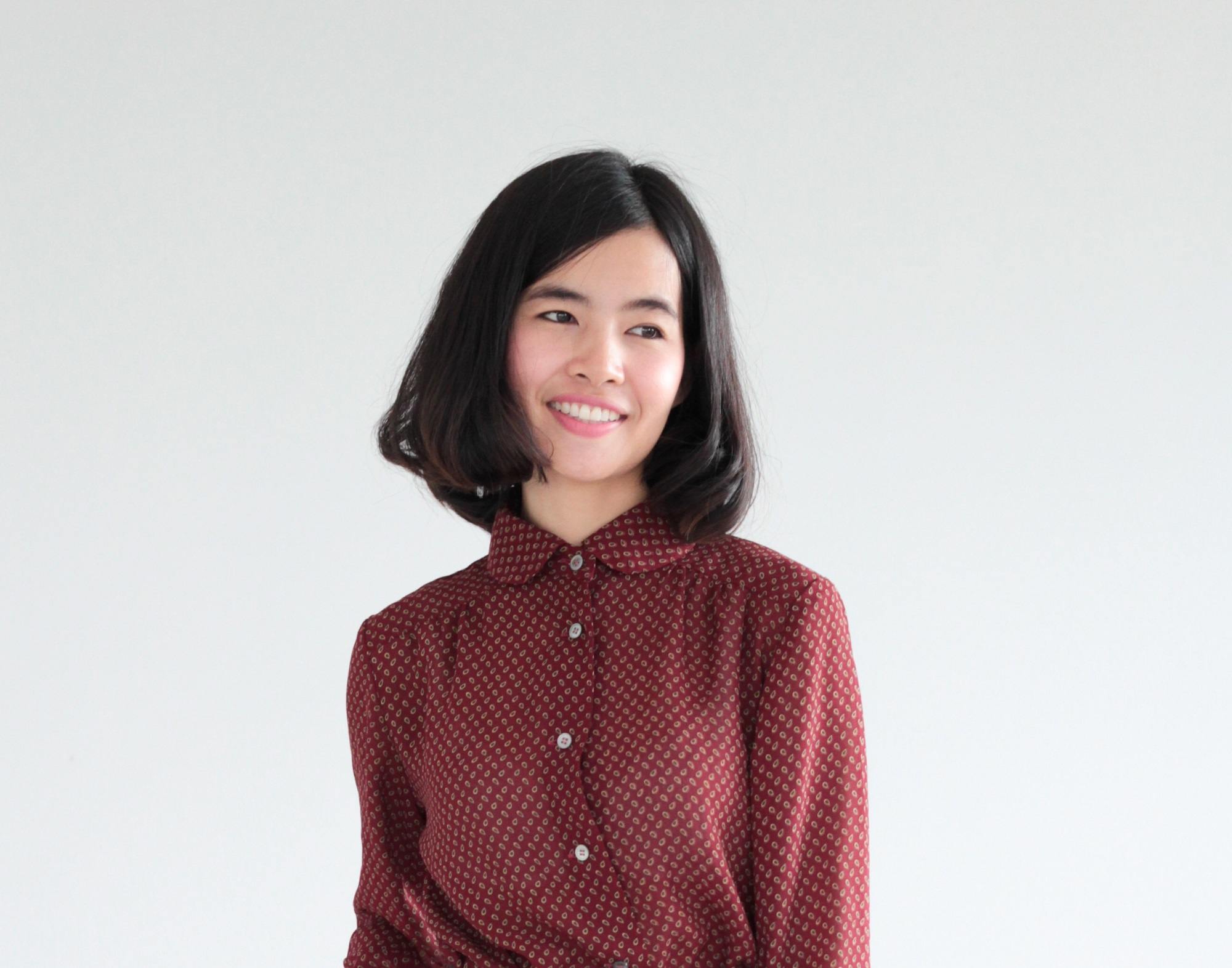 Chin length hairstyles: Asian woman wearing brown long sleeved polo with bob haircut against a white background