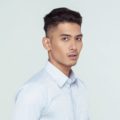 Shaved side hairstyles men: Asian man wearing a white collared polo with shaved side hairstyle and clean cut hairand short hair standing against a white background