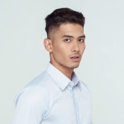 Shaved side hairstyles men: Asian man wearing a white collared polo with shaved side hairstyle and clean cut hairand short hair standing against a white background