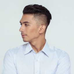 Shaved side hairstyles men: Asian man wearing a white long-sleeved polo with shaved side hairstyle and short hair against white background