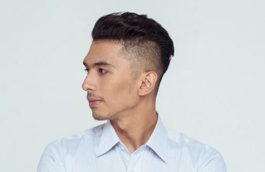 Shaved side hairstyles men: Asian man wearing a white long-sleeved polo with shaved side hairstyle and short hair against white background