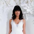 Wedding hairstyles for medium hair. Woman in a wedding dress with black shoulder-length wavy hair with bangs against a white background of cut out leaves and flowers