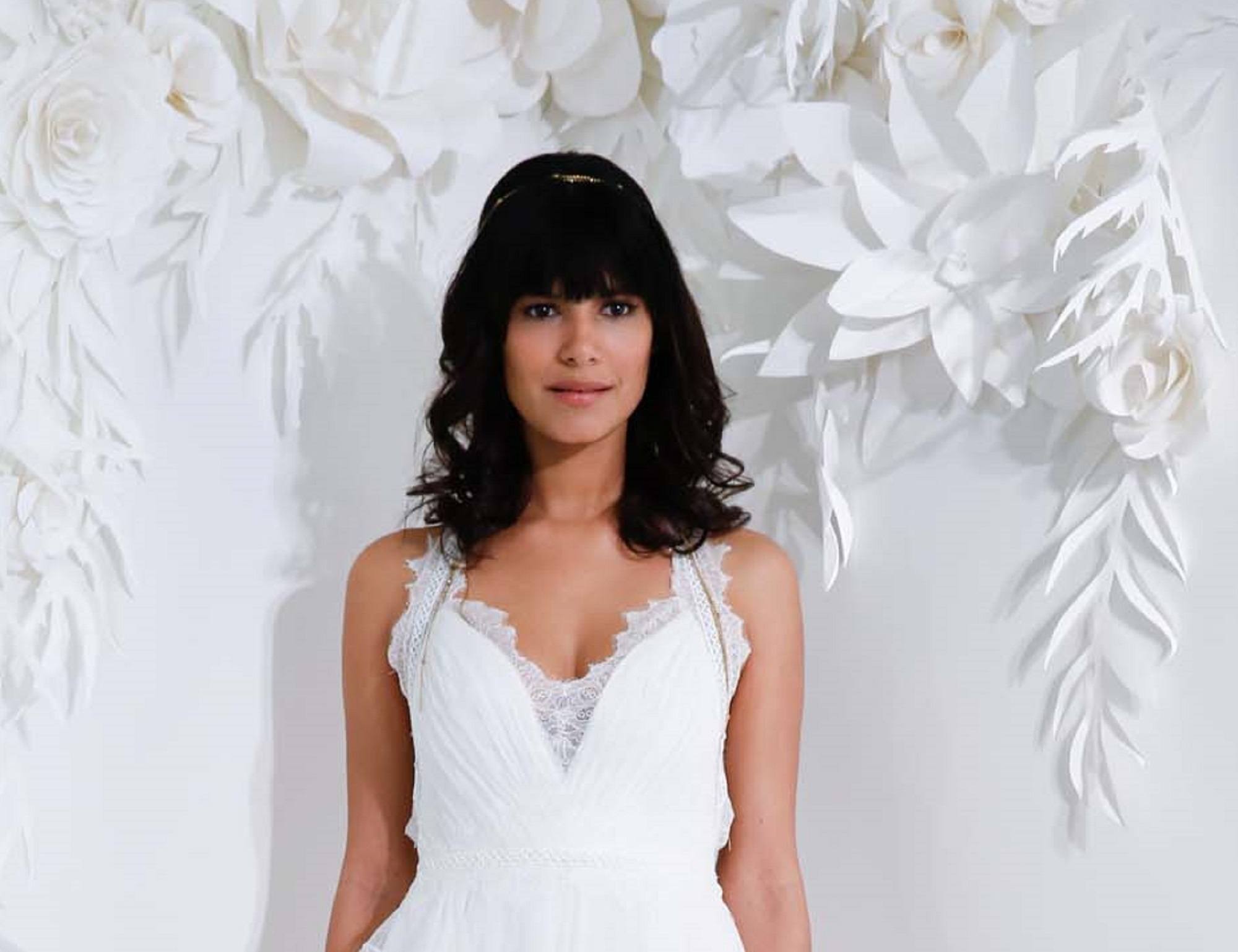 Wedding hairstyles for medium hair. Woman in a wedding dress with black shoulder-length wavy hair with bangs against a white background of cut out leaves and flowers