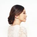 Wedding hairstyles for medium hair: Asian woman wearing light pink dress with dark brown hair in braided updo against a white background