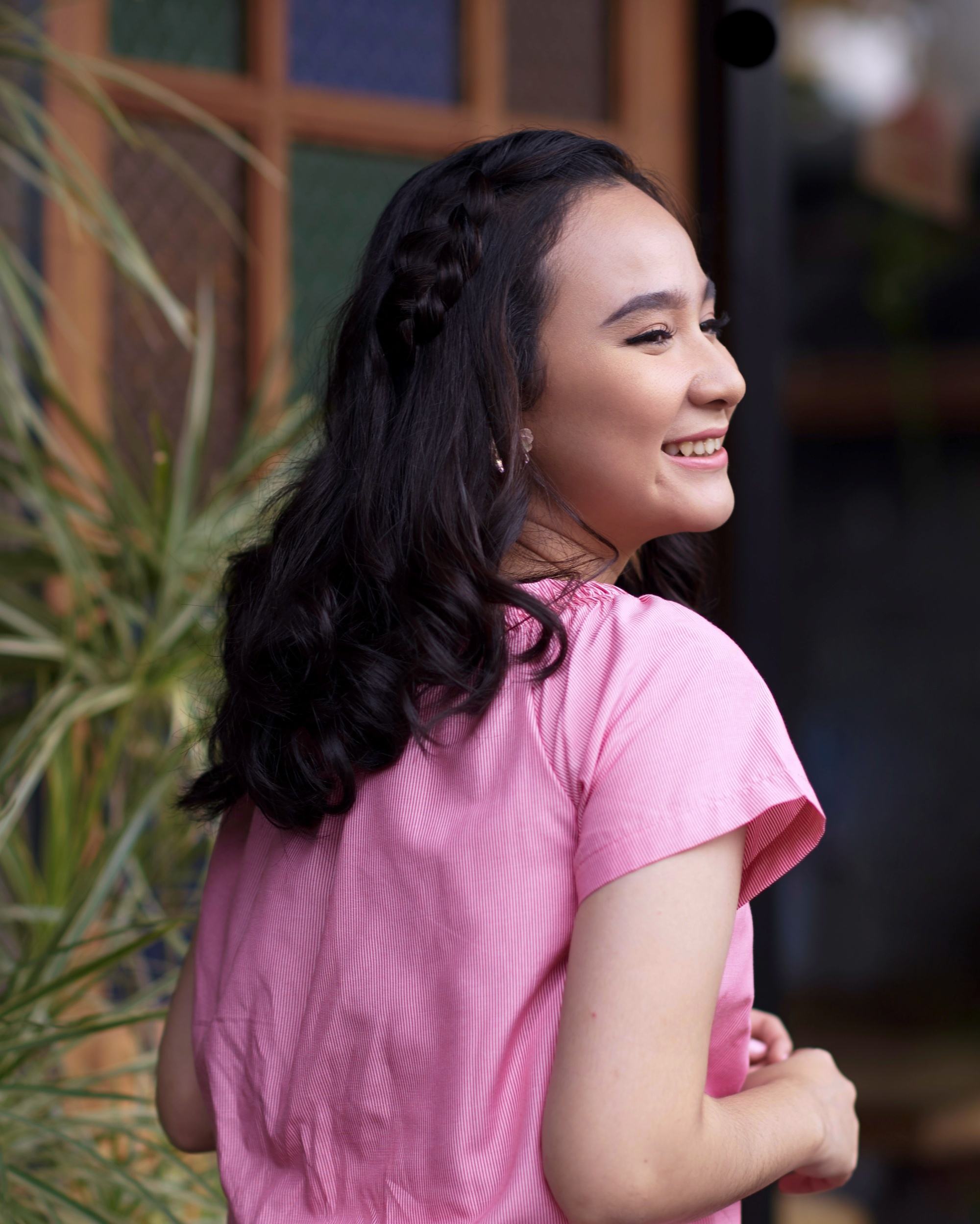 Asian woman with black hair in a headband braid hairstyle wearing a pink dress
