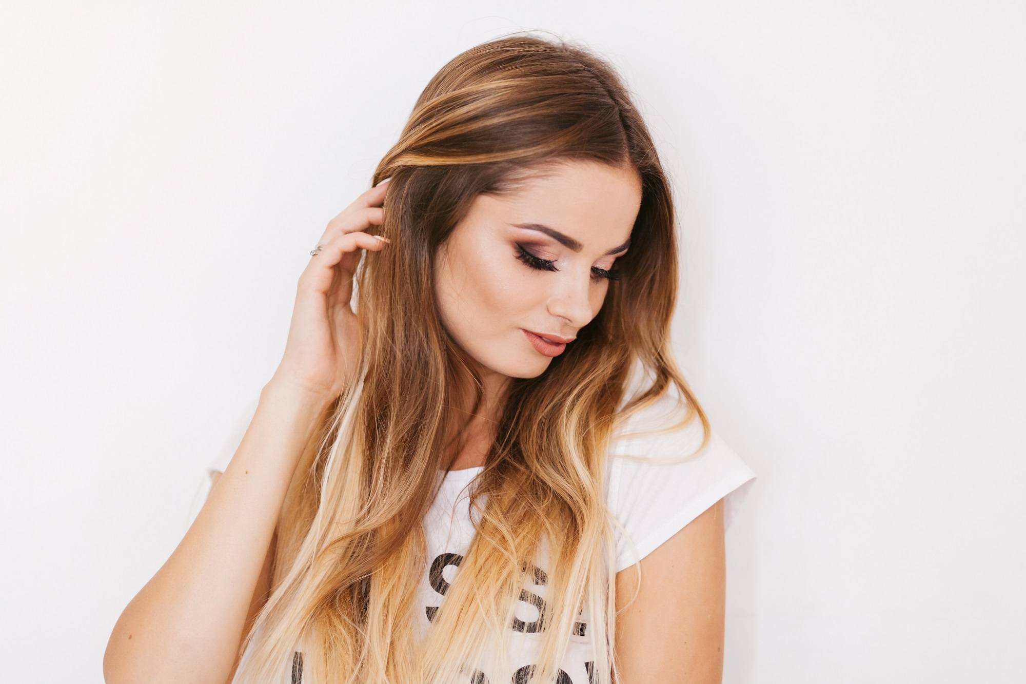 Brown ombre hair: Woman wearing a white shirt with brown ombre hear looking at the side