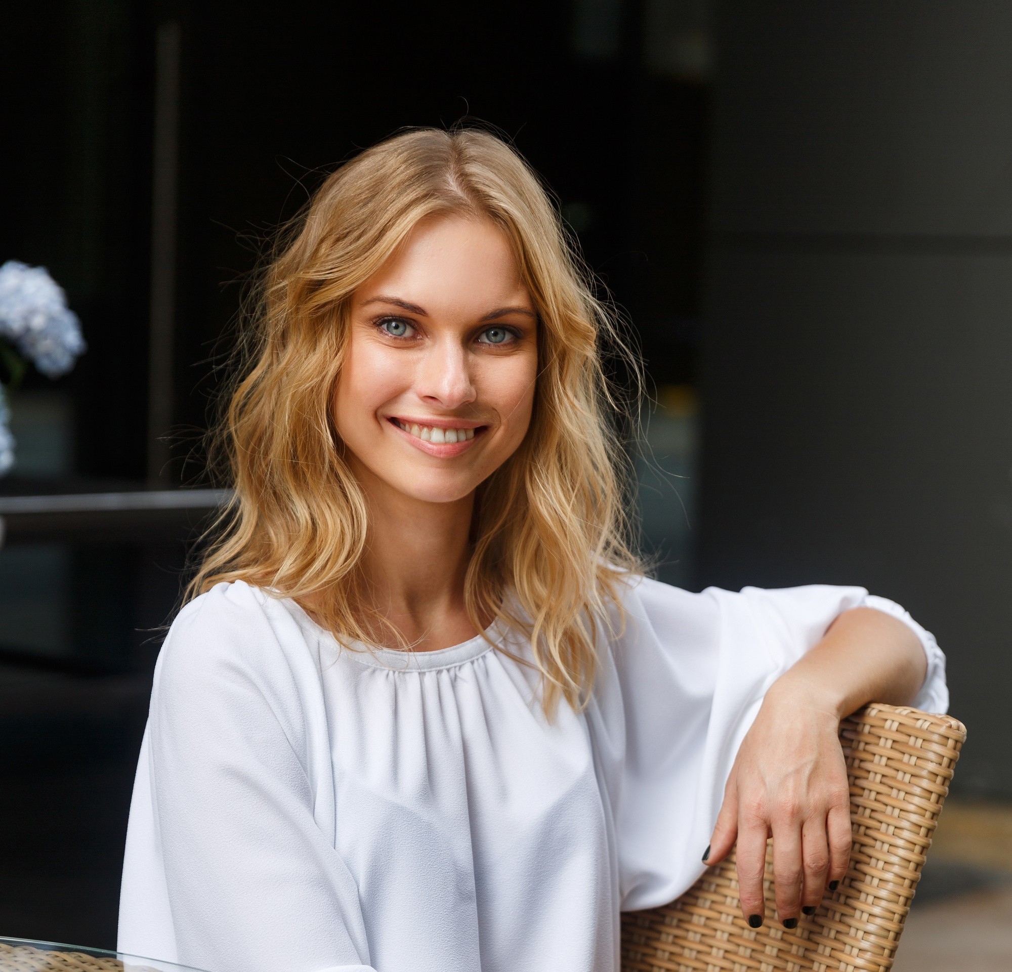 Honey blonde: Closeup shot of Caucasian woman with blonde shoulder-length hair wearing white blouse against a black background