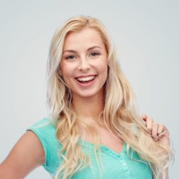 Light blonde hair: Woman with long blonde hair wearing a green top standing against a light gray background