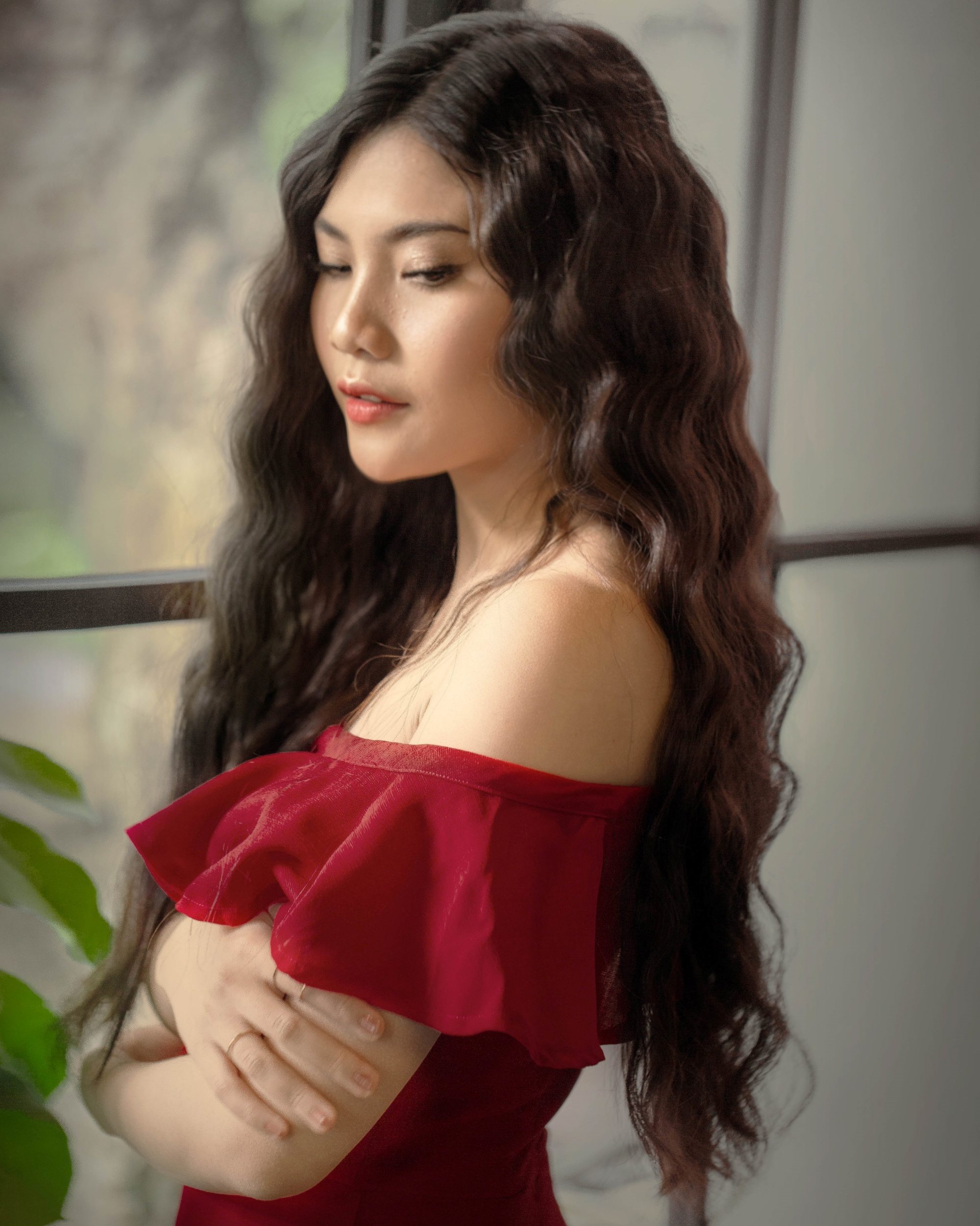 Femme asiatique avec de longs cheveux noirs d'Asteria portant une robe rouge à épaules dénudées