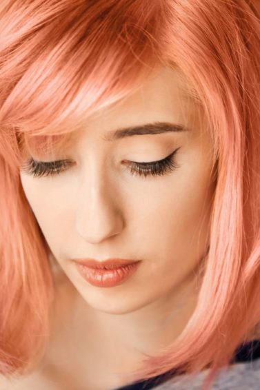 Orange hair: Closeup shot of a girl with apricot hair against a light gray background