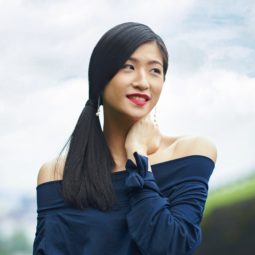 Side ponytail: Asian woman wearing darl blue blouse with long black hair in side ponytail in outdoor location