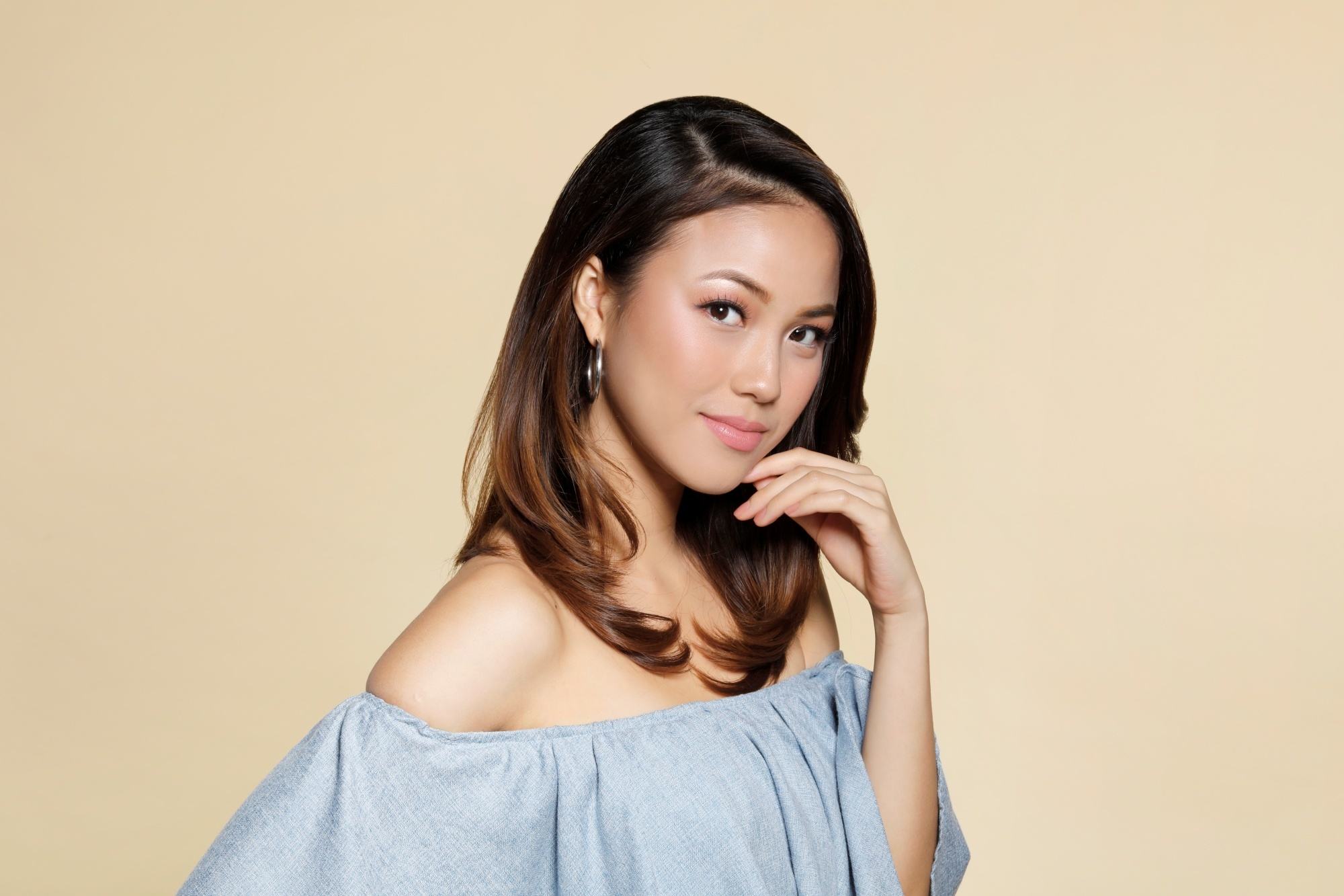 Asian woman with long layered hair wearing an off-shoulder-top