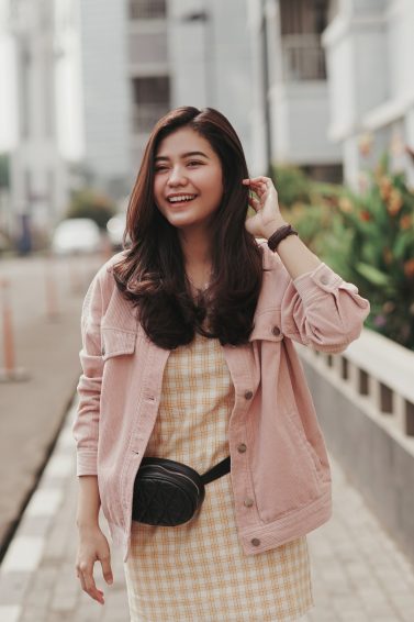Asian woman with long layered brown hair wearing a pink jacket outdoors