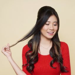 Christmas party hairstyles: Closeup shot of an Asian woman with long dark hair in beehive hairstyle wearing a red dress