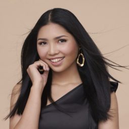 Cream Silk Glamorously Straight Hair: Closeup shot of an Asian woman with long black straight hair wearing a black top against an oyster-colored background