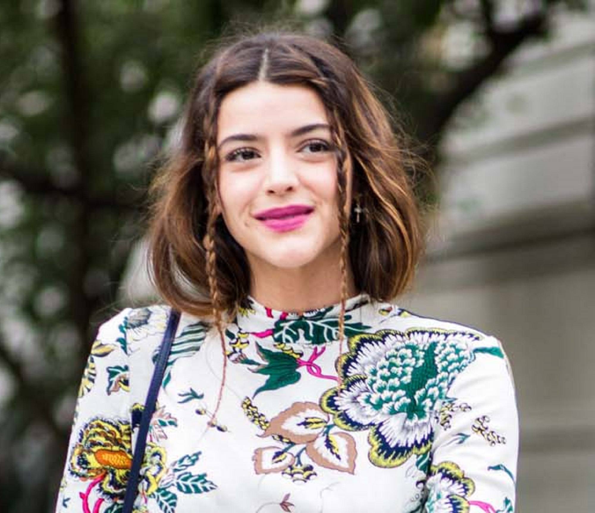 Frizzy hairstyles: Closeup shot of a woman with short hair with braids wearing a printed dress outdoors