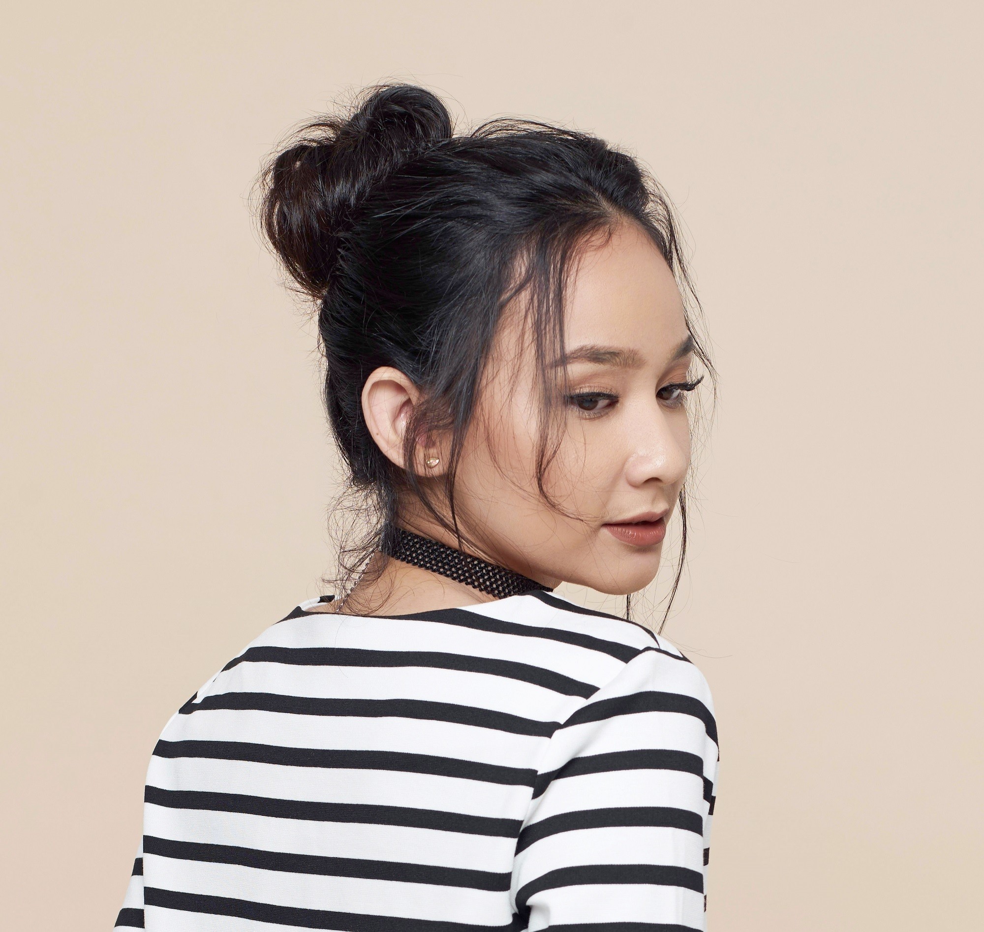 Frizy hairstyles: Closeup shot of an Asian woman with long black hair in a messy bun
