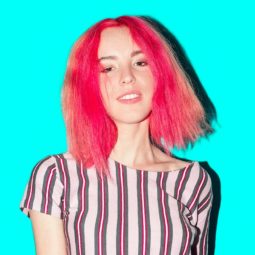 Hair trends to try in 2019: Closeup shot of a woman with pink long bob wearing a striped shirt against an aqua background