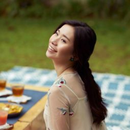 Half ponytail: Asian woman with long dark hair in braided half updo wearing a dress and sitting on a picnic mat
