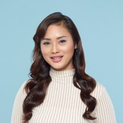 Curly hair prom: Asian woman with long hair with curly side fringe wearing a white turtleneck top