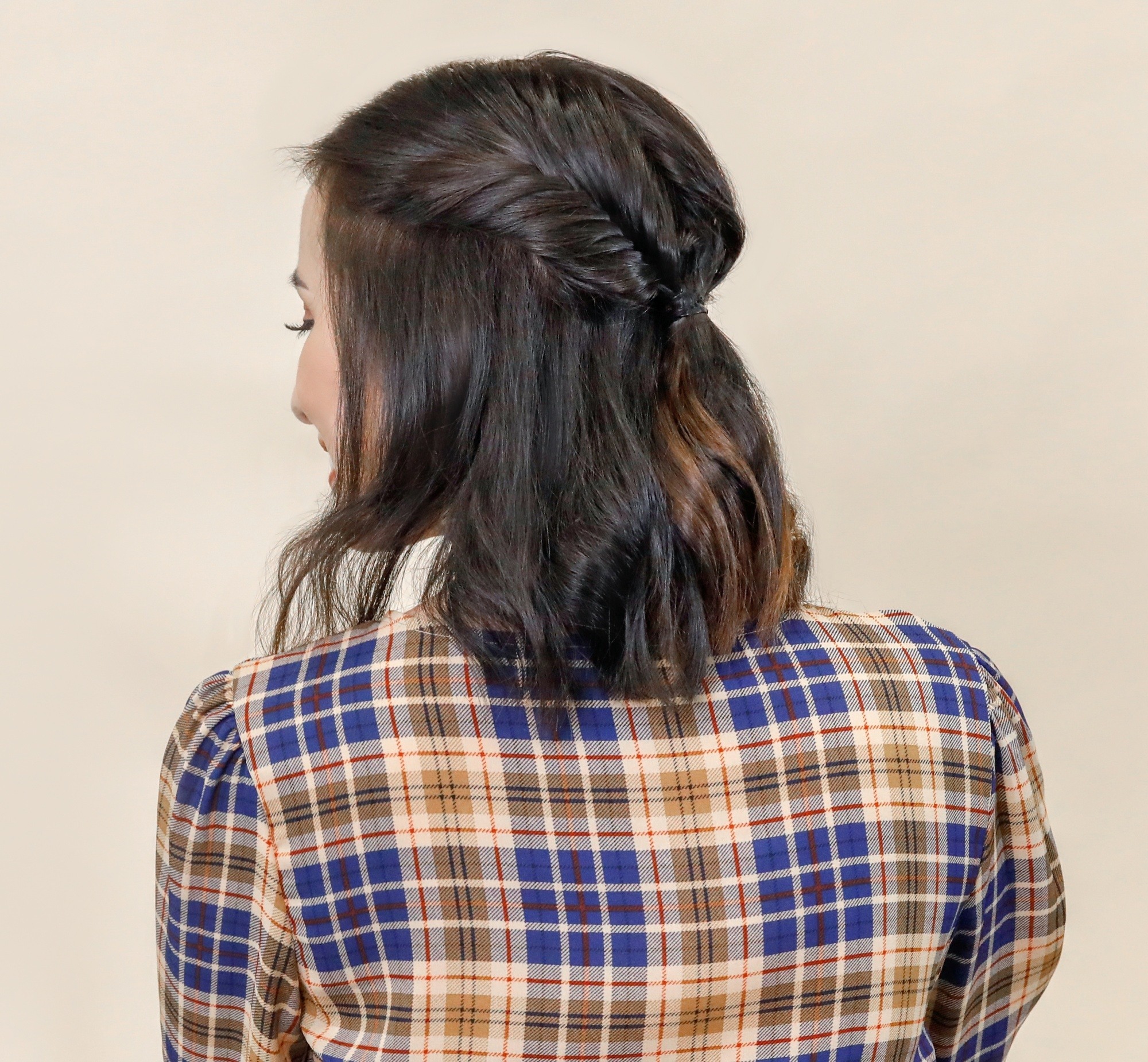 New Year's Eve Hairstyles: Back shot of an Asian woman with half up fishtail braid wearing a plaid top