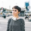Should I get bangs: Woman with black pixie cut wearing a long-sleeved striped shirt outdoors