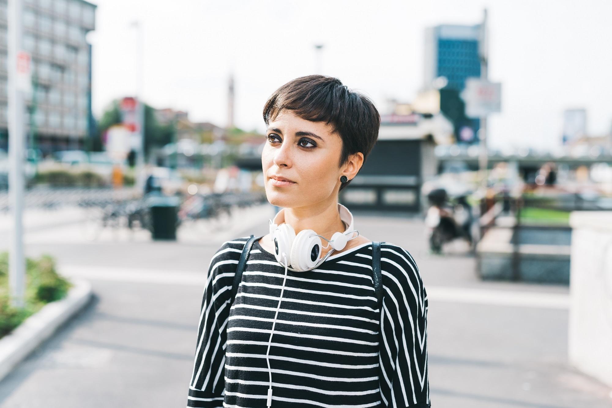 Should I get bangs: Woman with black pixie cut wearing a long-sleeved striped shirt outdoors