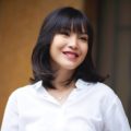 Should I get bangs: Asian woman with black shoulder-length hair with bangs wearing a white blouse outdoors