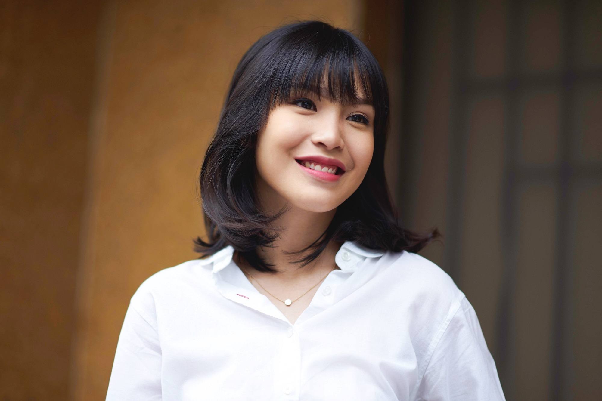 Should I get bangs: Asian woman with black shoulder-length hair with bangs wearing a white blouse outdoors