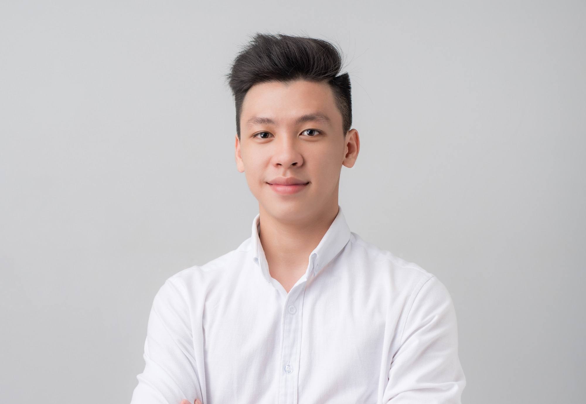 New hairstyles for men: Asian man with short black hair in pompadour hairstyle wearing a white long-sleeved polo