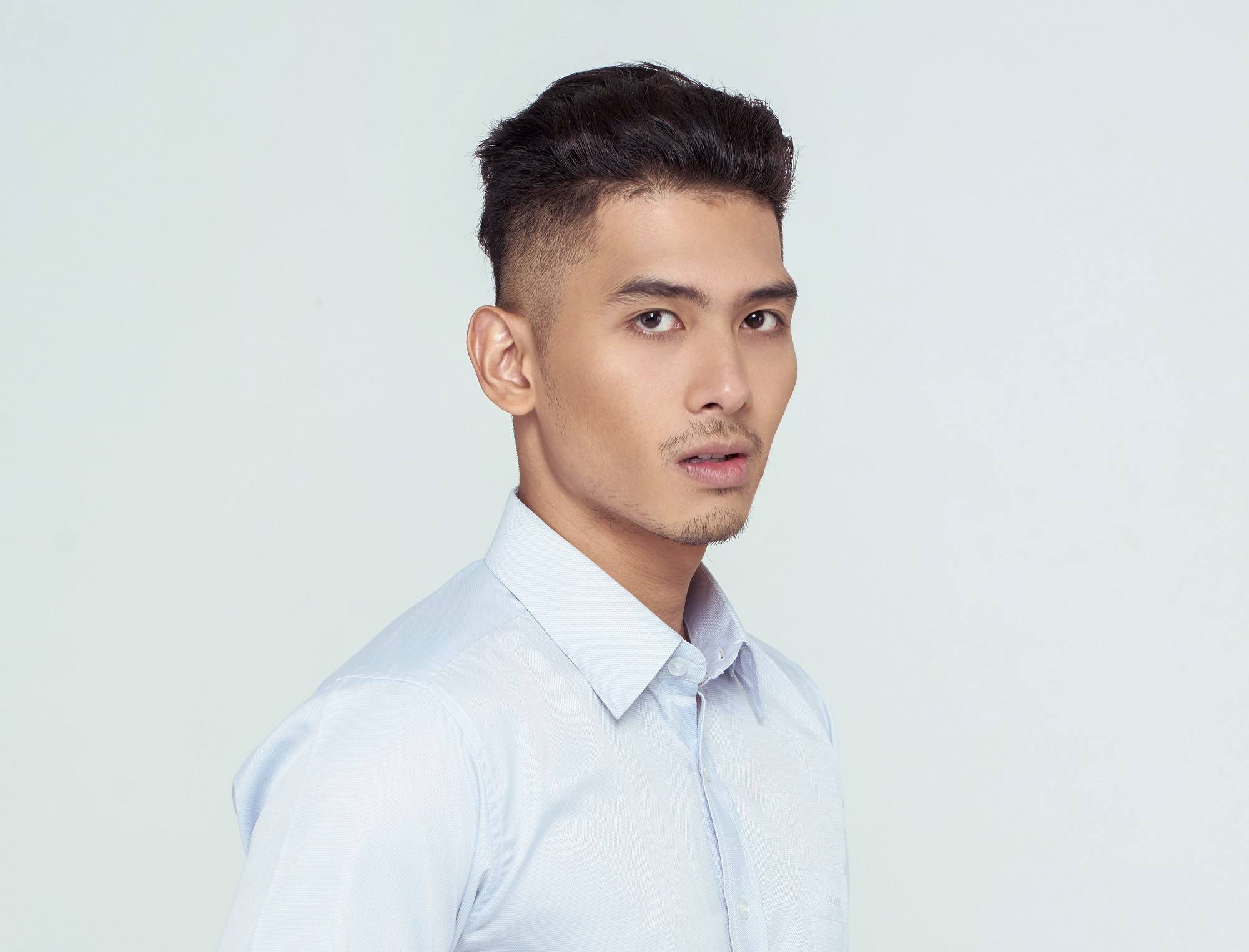 New hairstyles for men: Asian man with short black hair with shaved side and wearing a white button-down polo