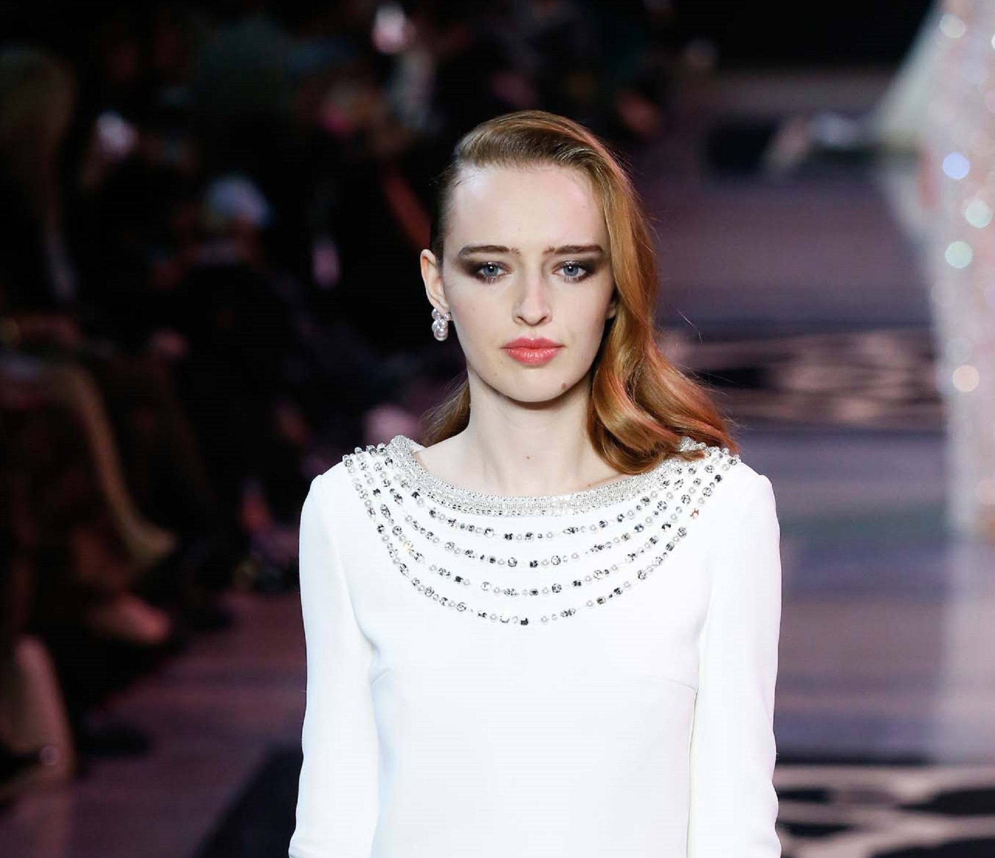 Paris Fashion Week 2019: Woman with brown flipped-out shoulder length hair wearing a white dress on the runway