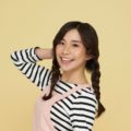 Simple braids: Asian woman wearing a pink jumper and striped long-sleeved shirt with long dark hair in twin braids