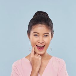 Sock bun: Closeup shot of an Asian woman with long black hair in a bun and wearing a pink blouse