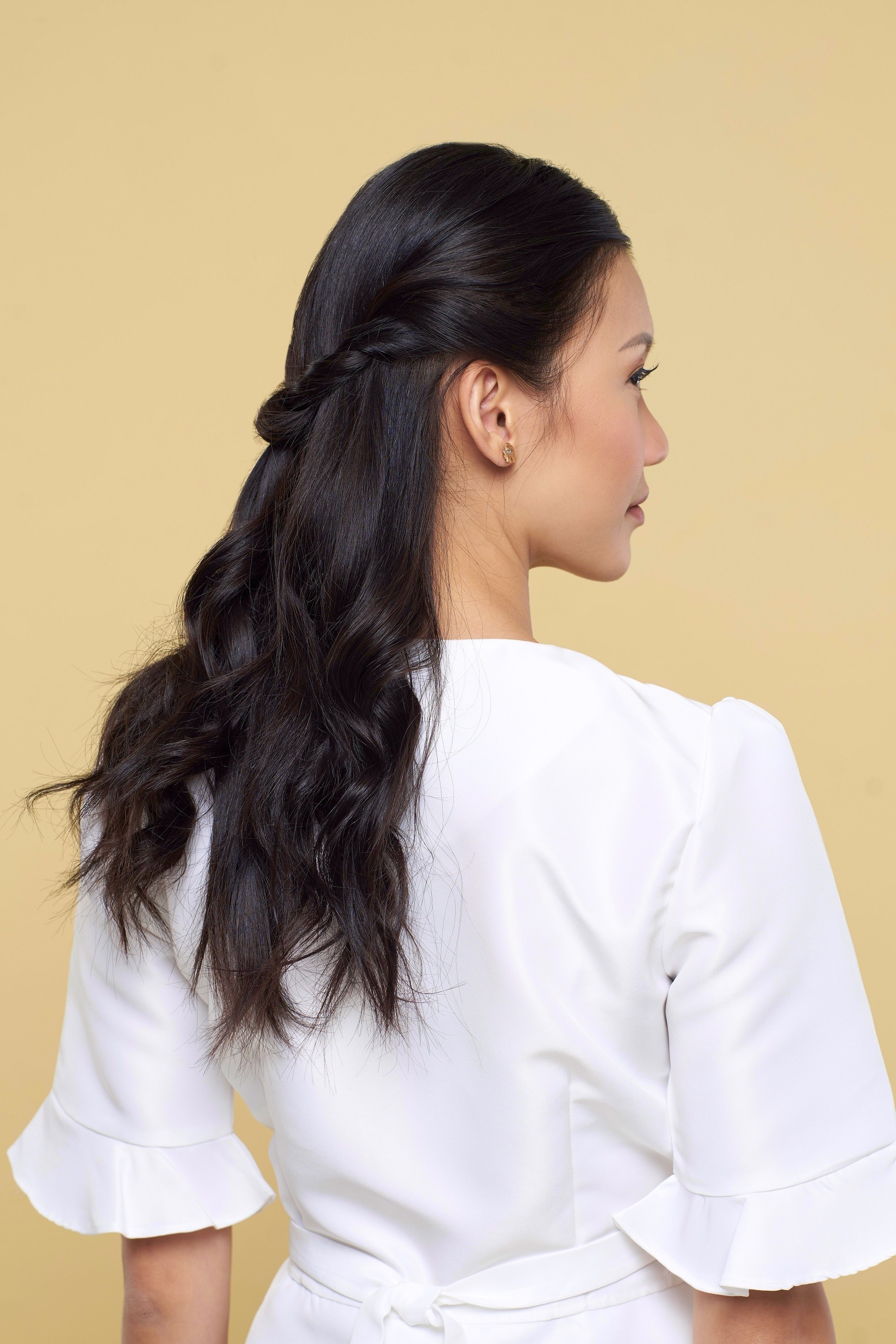 Valentine hairstyles: Back shot of an Asian woman with long black hair in half updo wearing a white blouse