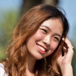 Medium brown hair color: Asian woman with golden copper brown hair smiling