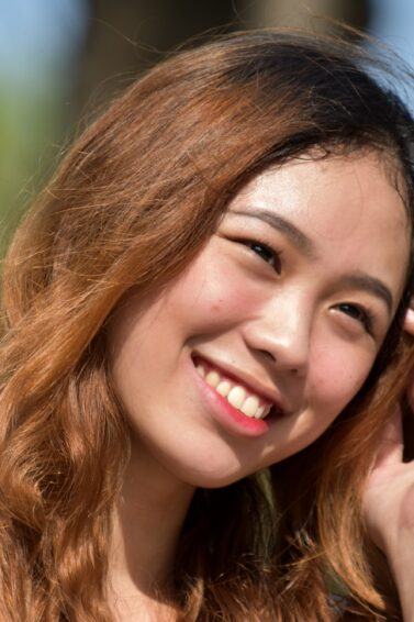 Medium brown hair color: Asian woman with golden copper brown hair smiling