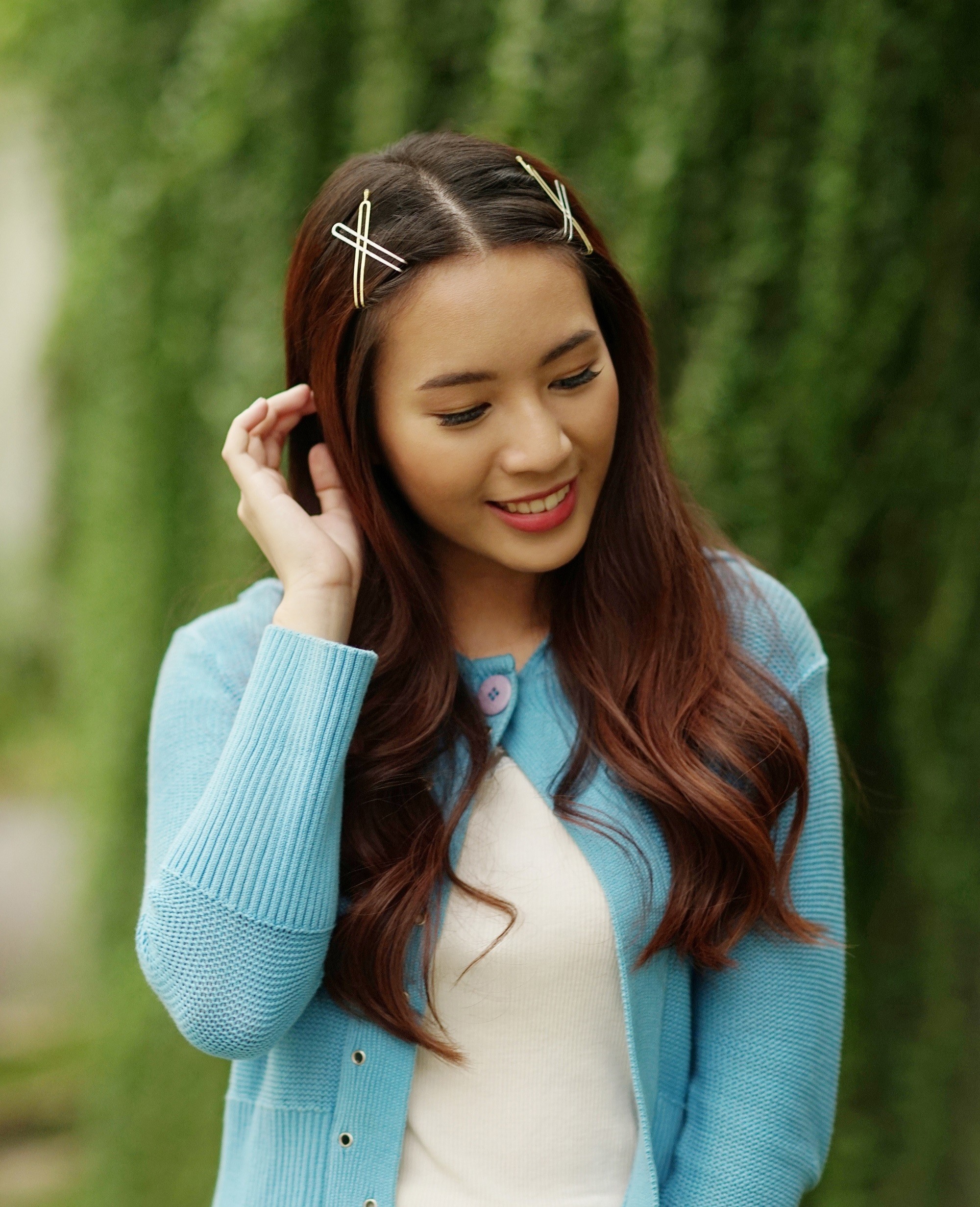 Asian woman with long dark brown ha wearing a blue cardigan outdoors