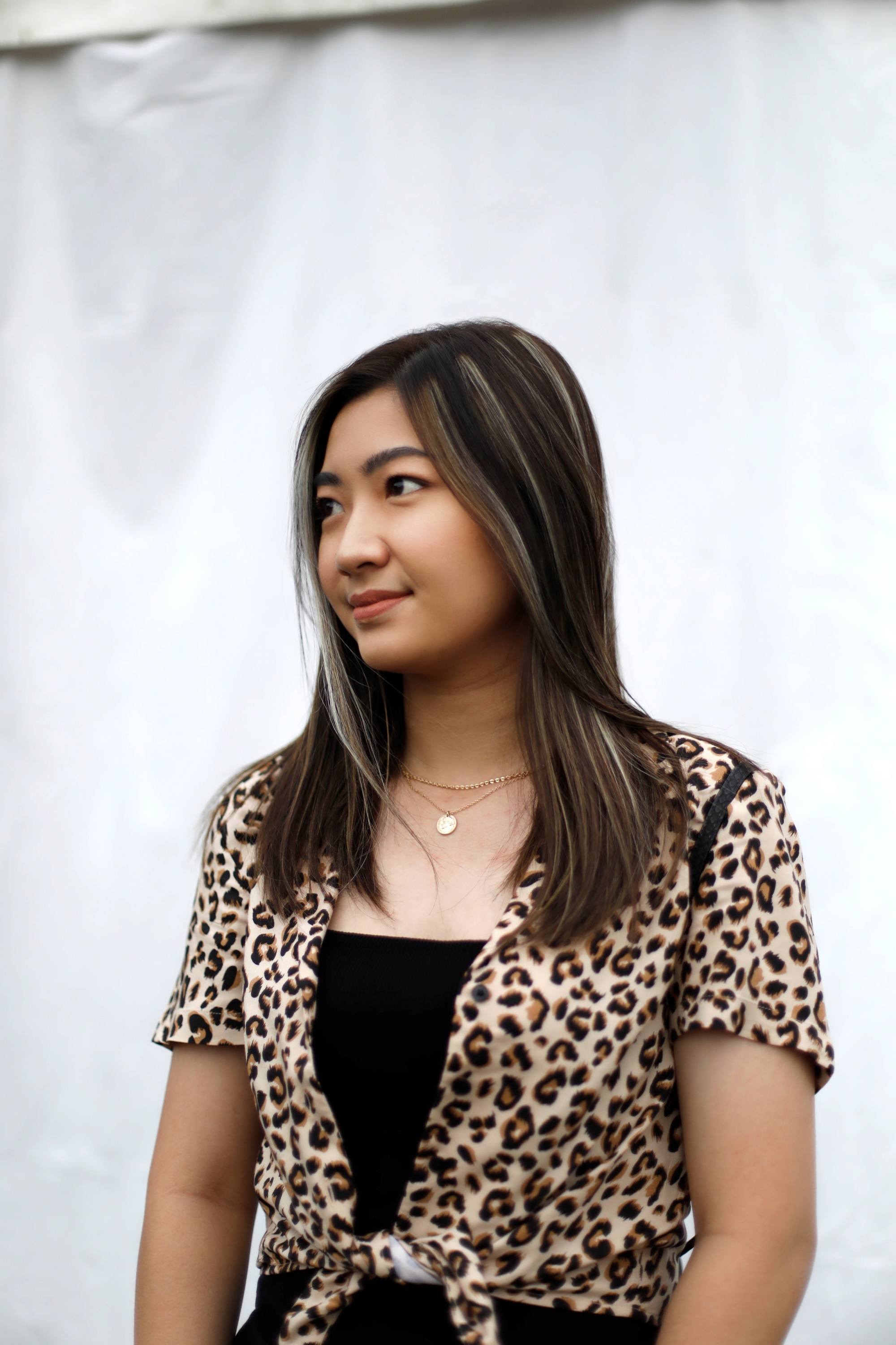 Asian woman with long dark hair with gray streaks wearig a leopard-print