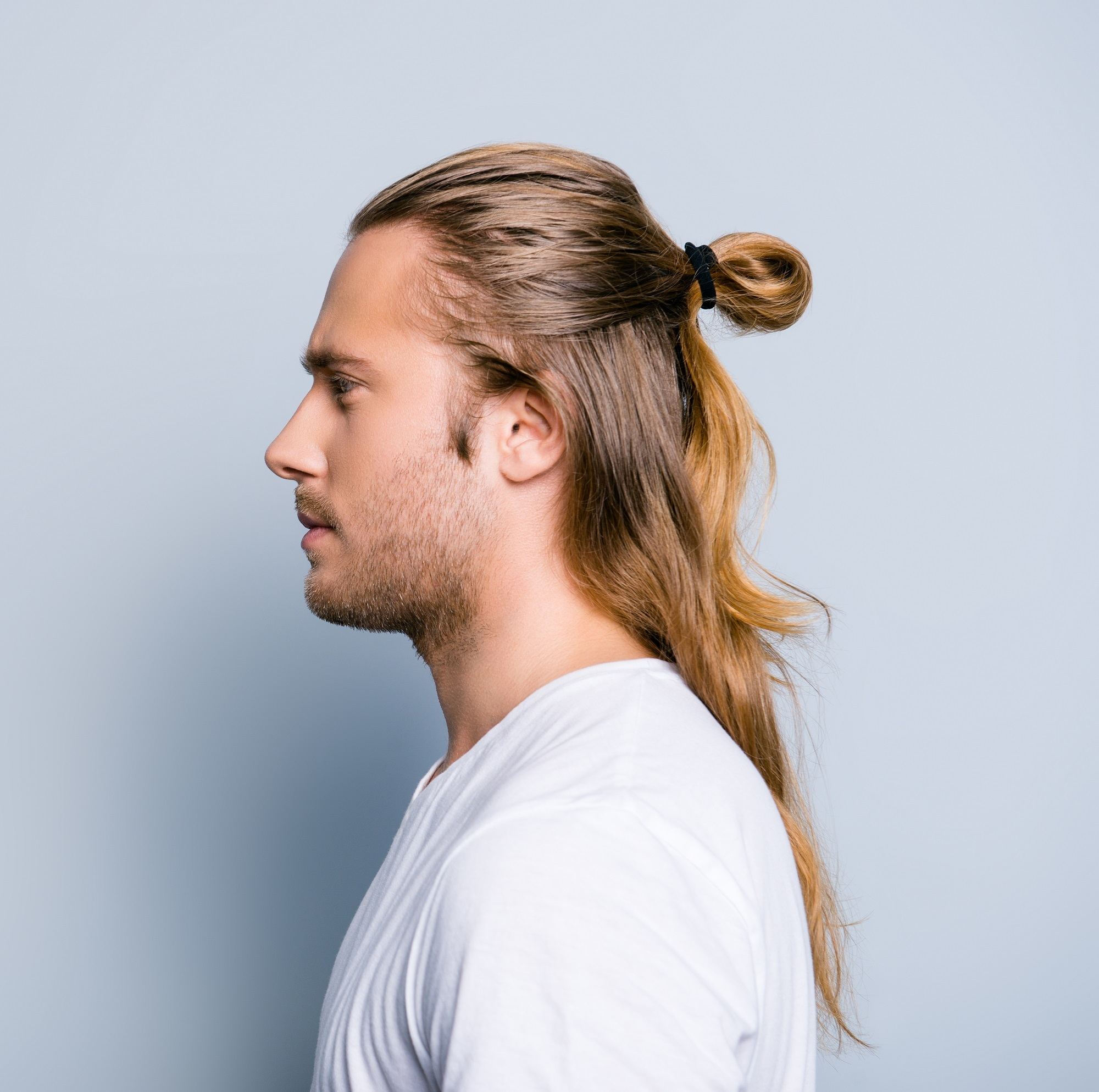 Man ponytail: Side view of a man with long brown hair in a half ponytail